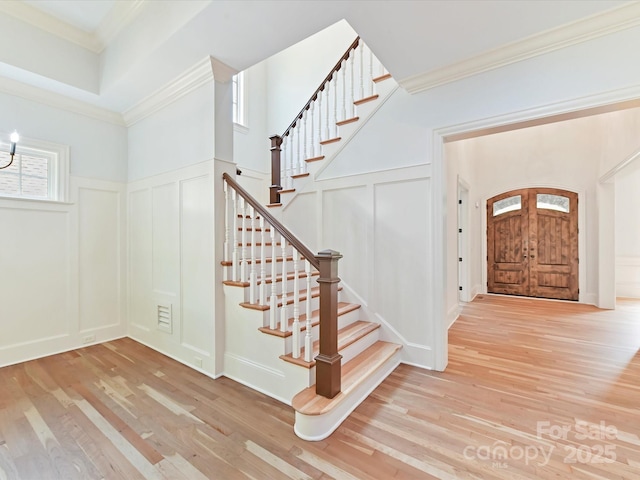 entryway featuring stairway, a decorative wall, and wood finished floors