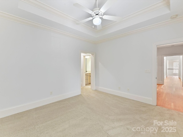 unfurnished room featuring light carpet, crown molding, and a raised ceiling