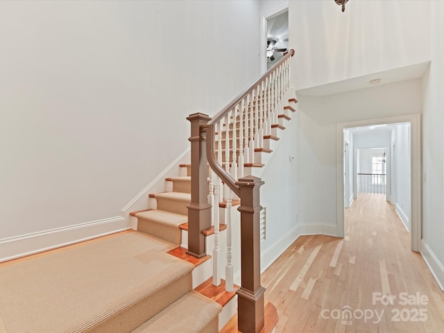staircase with baseboards and wood finished floors