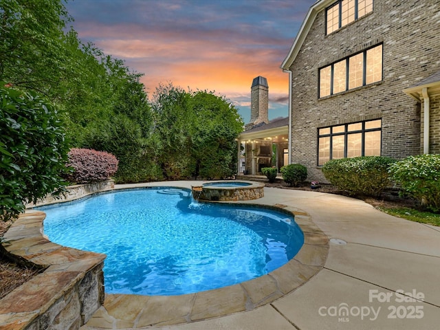 pool at dusk with a patio and a pool with connected hot tub