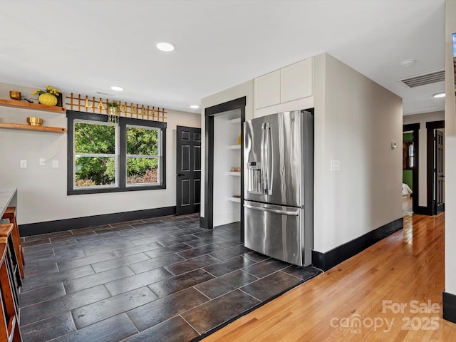 kitchen with open shelves, stainless steel fridge, white cabinets, baseboards, and visible vents