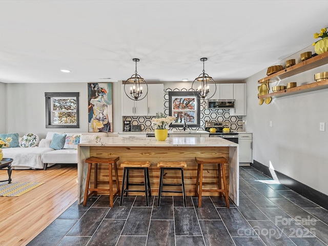 kitchen featuring tasteful backsplash, an inviting chandelier, stainless steel appliances, a kitchen bar, and white cabinetry
