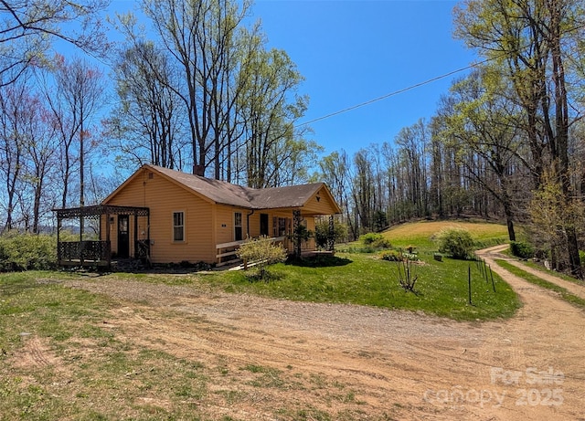 view of side of home with a lawn, a wooden deck, and dirt driveway