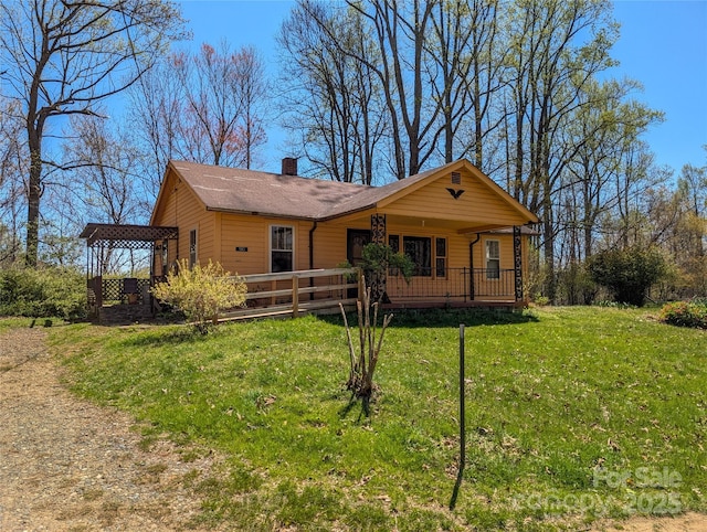 ranch-style house featuring covered porch, a front lawn, and a chimney