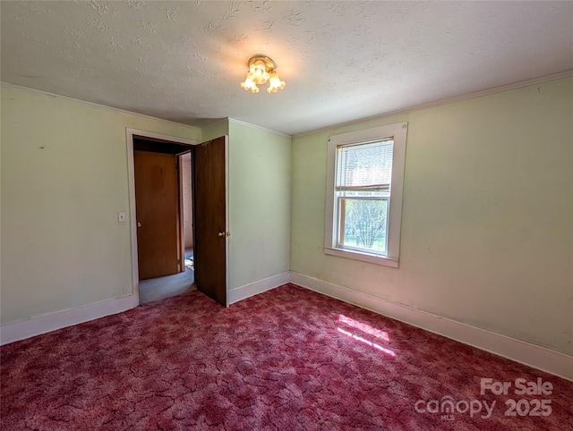 empty room with baseboards, crown molding, a textured ceiling, and carpet