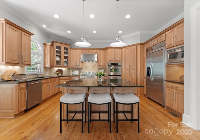 kitchen with built in appliances, extractor fan, a center island, a sink, and a breakfast bar