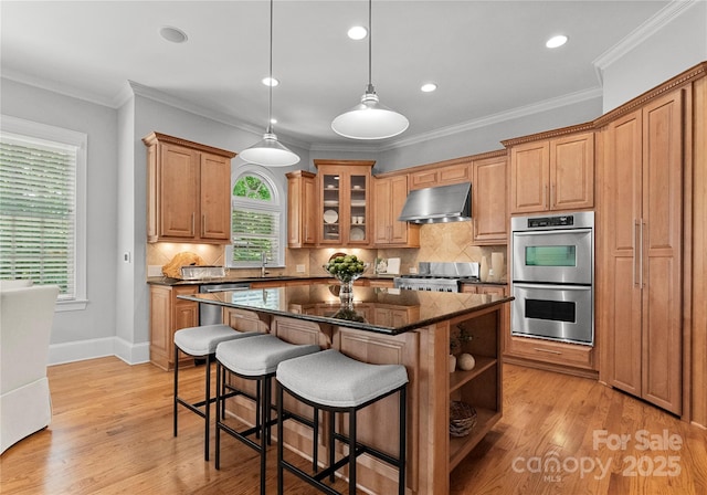 kitchen featuring ventilation hood, stainless steel double oven, stove, a sink, and a center island