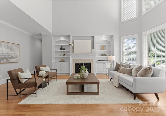 7005 Camrose Crossing Ln, Matthews, NC 28104 - living area with a towering ceiling, built in features, ornamental molding, light wood finished floors, and a glass covered fireplace