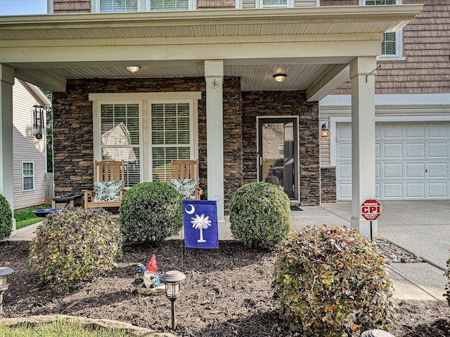 entrance to property featuring a porch, stone siding, and a garage
