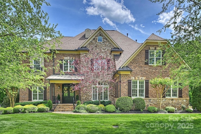 view of front of home with brick siding, stone siding, a shingled roof, and a front yard