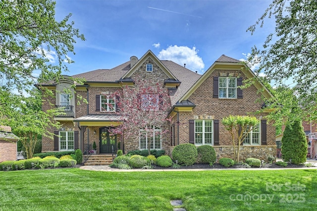 craftsman-style home featuring brick siding, stone siding, and a front yard