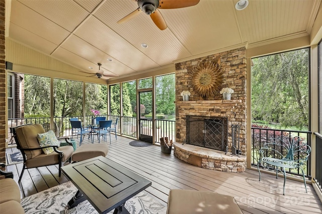 sunroom with an outdoor stone fireplace and ceiling fan