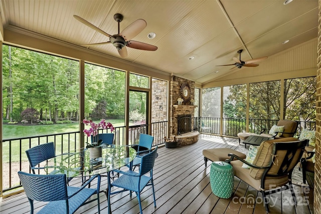 sunroom / solarium with outdoor dining area, ceiling fan, and a stone fireplace