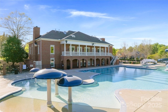 community pool with fence, stairs, and a patio