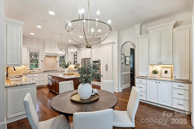 2001 Arundale Ln, Matthews, NC 28104 - dining area featuring crown molding, arched walkways, dark wood finished floors, an inviting chandelier, and recessed lighting