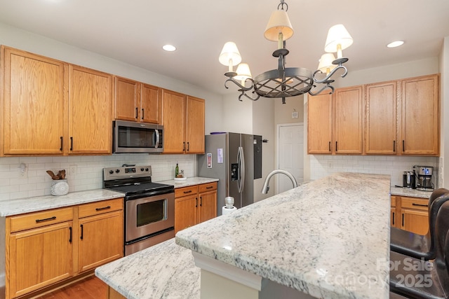 9904 Rocky Ford Club Rd, Charlotte, NC 28269 - kitchen with stainless steel appliances, decorative backsplash, a notable chandelier, light stone counters, and wood finished floors