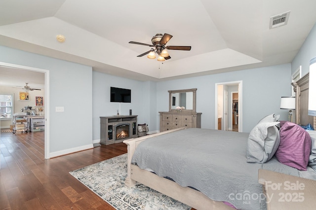 9904 Rocky Ford Club Rd, Charlotte, NC 28269 - bedroom featuring dark wood finished floors, visible vents, a lit fireplace, and a tray ceiling