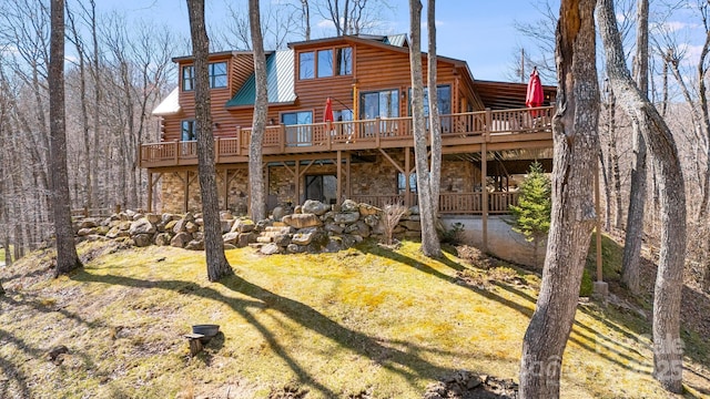 rear view of property featuring log exterior, a wooden deck, and stone siding