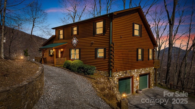 view of front of house featuring stone siding, an attached garage, and aphalt driveway