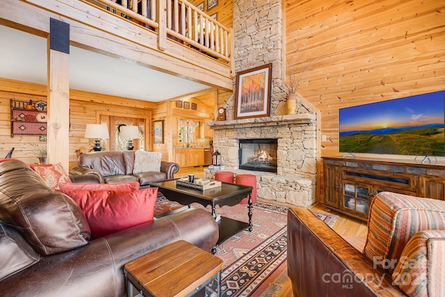 living room with wooden walls, a high ceiling, and a fireplace
