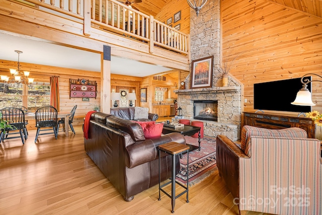 living room with wooden walls, a towering ceiling, a chandelier, and a fireplace