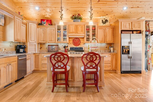 kitchen featuring recessed lighting, stainless steel appliances, glass insert cabinets, light wood-type flooring, and a kitchen island