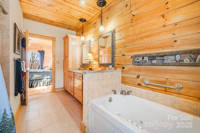 ensuite bathroom with wooden ceiling, tile patterned floors, vanity, baseboards, and a jetted tub