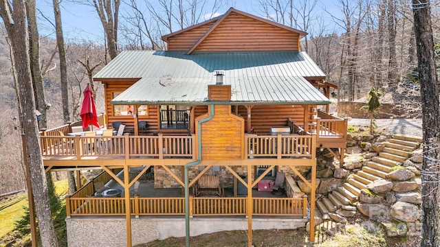 back of house with a wooden deck, metal roof, and log siding