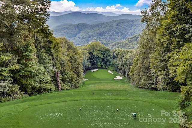 view of home's community with a mountain view, golf course view, and a view of trees