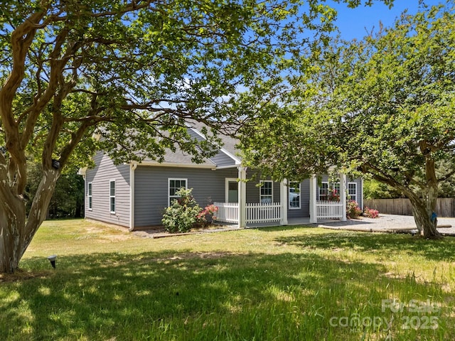 rear view of property featuring fence, a shingled roof, and a lawn