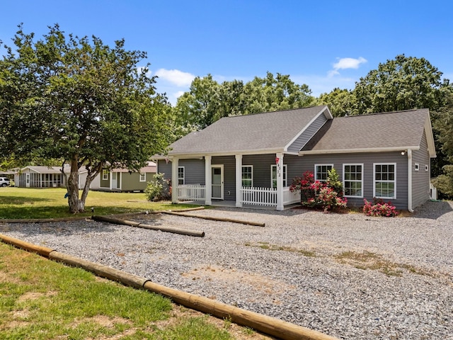 ranch-style home with a porch, a shingled roof, and a front yard