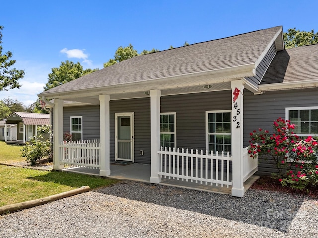 rear view of property featuring covered porch and a shingled roof