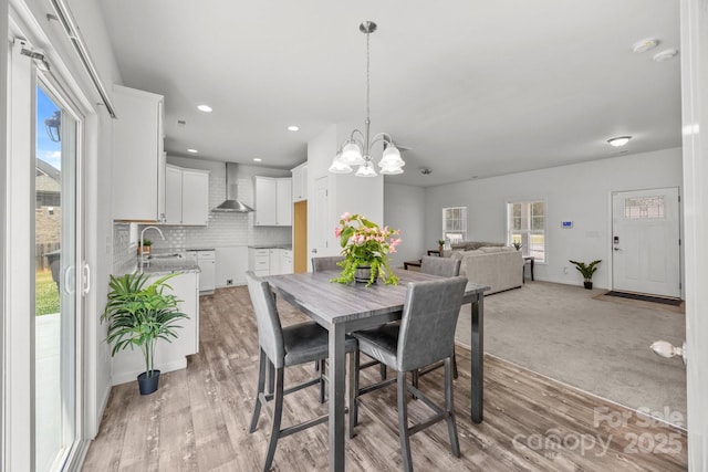 dining area featuring recessed lighting, light wood-style floors, a notable chandelier, and a wealth of natural light