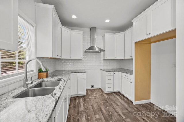 kitchen featuring dark wood-type flooring, a sink, wall chimney exhaust hood, and light stone countertops
