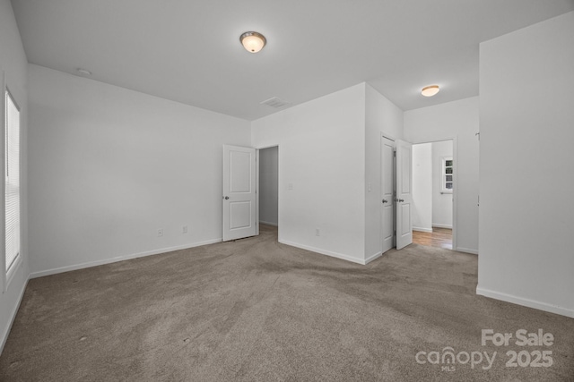 unfurnished bedroom featuring baseboards, carpet flooring, and visible vents