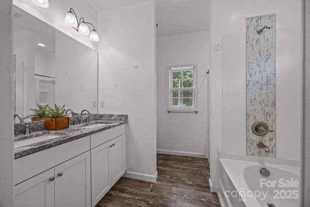 full bathroom with a sink, double vanity, shower / tub combination, and wood finished floors