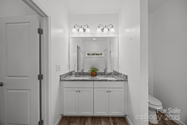 full bath with double vanity, a sink, wood finished floors, and toilet