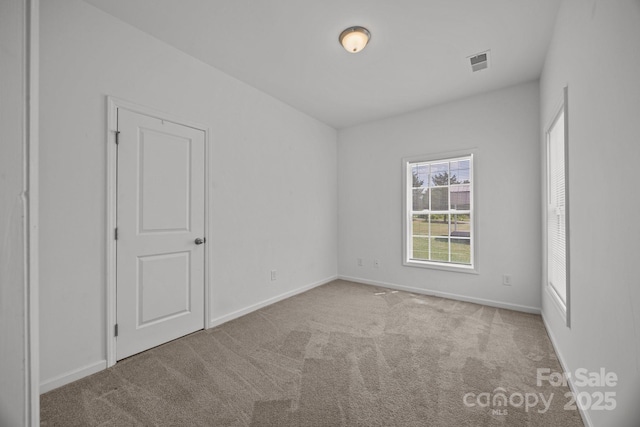 spare room featuring baseboards, visible vents, and carpet
