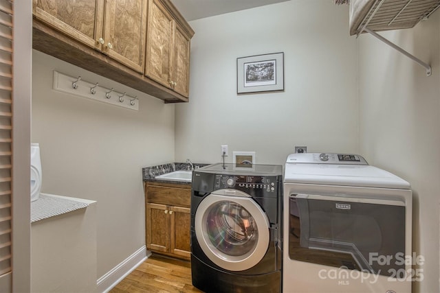 3 Kensington Ct, Granite Falls, NC 28630 - washroom with baseboards, cabinet space, washing machine and clothes dryer, a sink, and light wood-style flooring