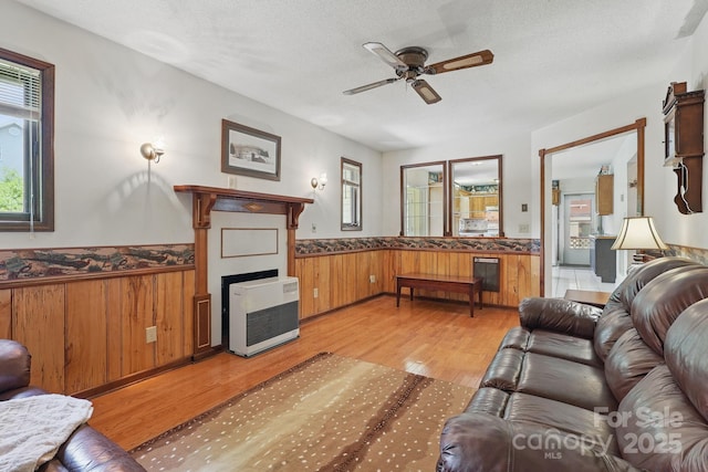 137 Clint Lewis Rd, Boone, NC 28607 - living room with heating unit, a ceiling fan, light wood-style flooring, a wainscoted wall, and a textured ceiling