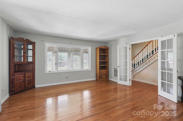 137 Clint Lewis Rd, Boone, NC 28607 - unfurnished living room featuring french doors, a textured ceiling, wood finished floors, stairway, and baseboards