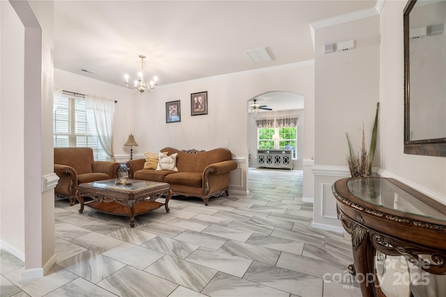 living area with a chandelier, ornamental molding, and arched walkways