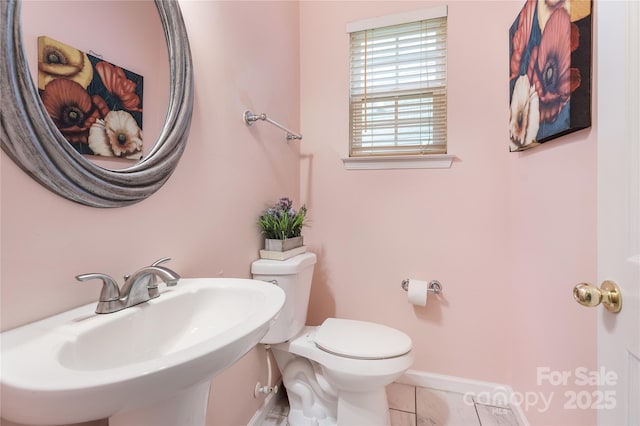 half bathroom with toilet, a sink, tile patterned floors, and baseboards