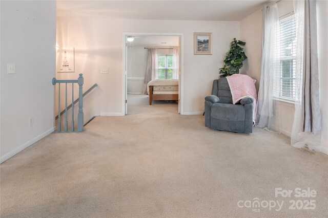 living area featuring baseboards, an upstairs landing, and carpet floors