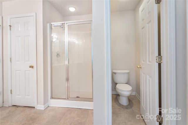 full bath with toilet, a stall shower, and baseboards