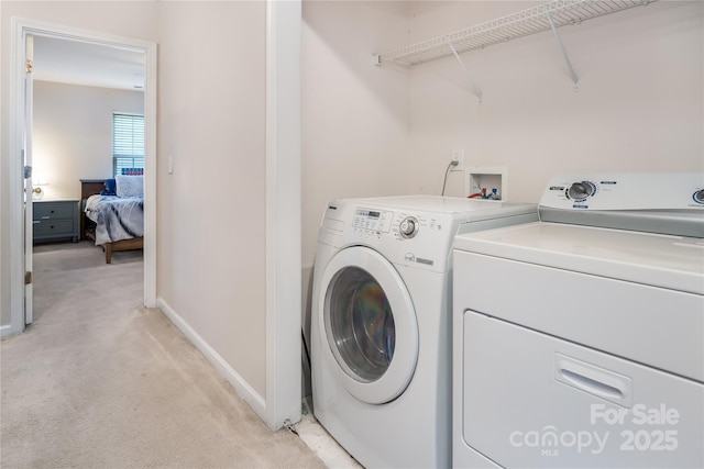 washroom featuring baseboards, washing machine and clothes dryer, laundry area, and light colored carpet