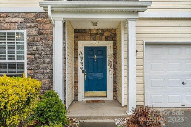 entrance to property featuring stone siding and a garage