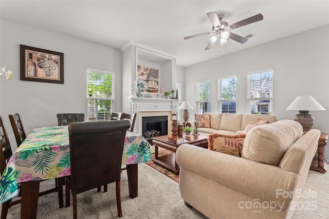 living room with light carpet, a ceiling fan, visible vents, and a glass covered fireplace