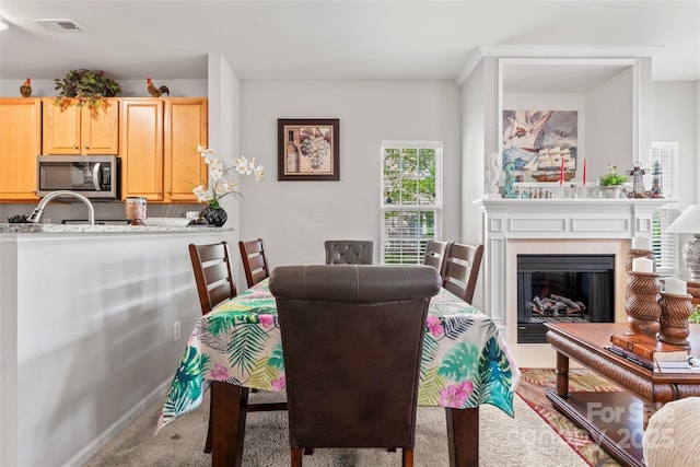 dining room featuring a glass covered fireplace, carpet flooring, and visible vents
