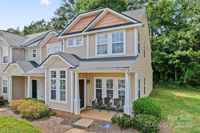 view of front of home with a shingled roof and a front lawn